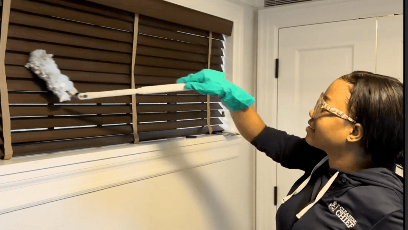 Cleaner dusting the window blinds with duster to provide VIP cleaning service