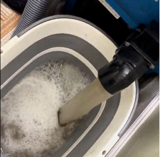 Container of dark dirty water extracted after deep carpet cleaning in a commercial property, showing before and after impact